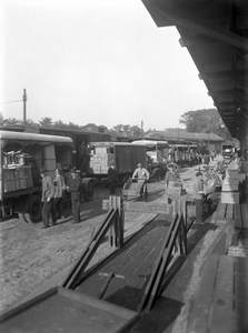 807269 Afbeelding van het overladen van stukgoederen naar vrachtauto's van Van Gend & Loos bij het N.S.-station ...